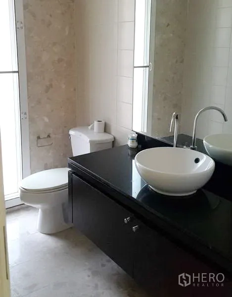 Detached House for rent in Wang Thonglang, Bangkok - Modern bathroom with vessel sink on black vanity, toilet and tall windows.
