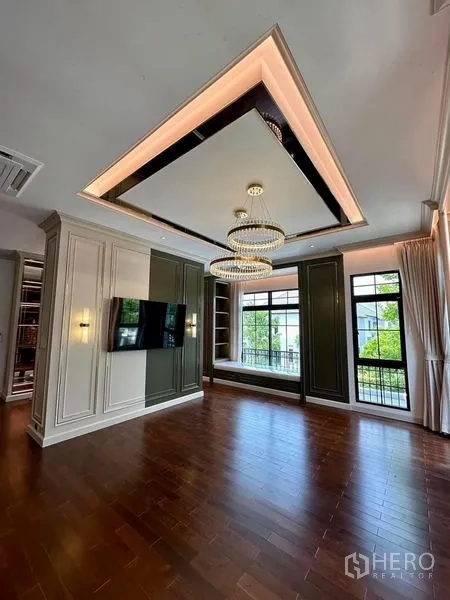 Detached House for sale - Elegant sitting room with paneled walls, statement chandelier and garden-facing windows.