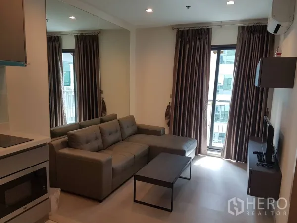 คอนโด ให้เช่าในKhlong Toei, Bangkok - มุมนั่งเล่นหันสู่ระเบียง ม่านทึบสูงจรดเพดาน และทีวีติดผนัง