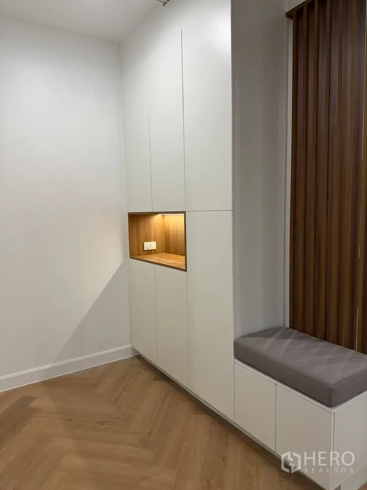 Condominium for rent in Watthana, Bangkok - Built-in cabinets with lit niche and bench seat beside wood slats.