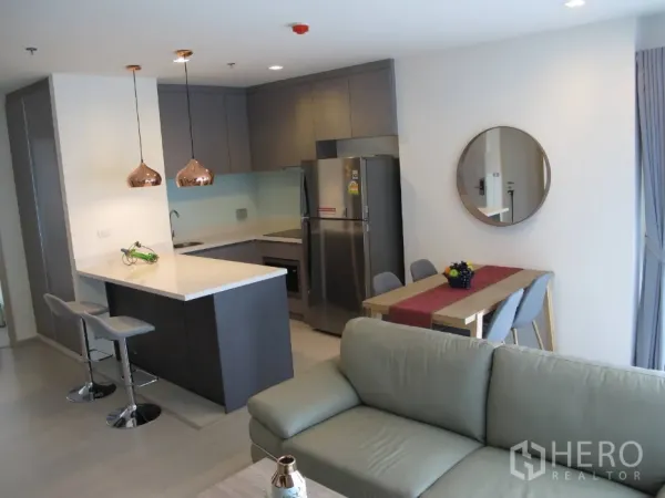 公寓 出租或出售在Khlong Toei, Bangkok - 开放式厨房，带中岛、铜色吊灯、用餐区与沙发。