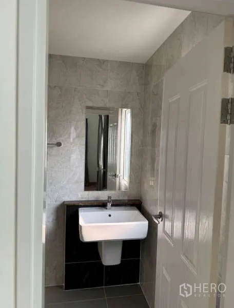 Detached House for rent in Bueng Kum, Bangkok - Compact bathroom with white sink, mirror and gray wall tiles.