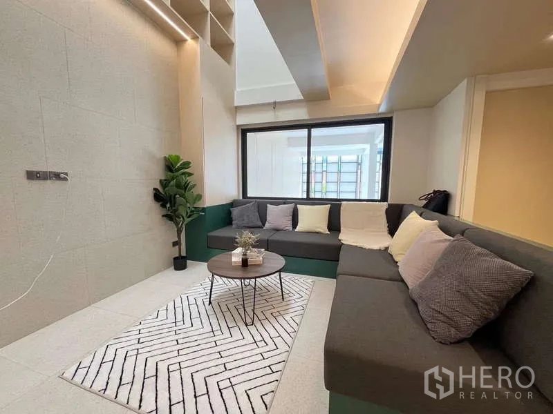 Townhouse for sale in Khlong Toei, Bangkok - Cozy living room with L-shaped sofa, coffee table and accent lighting.