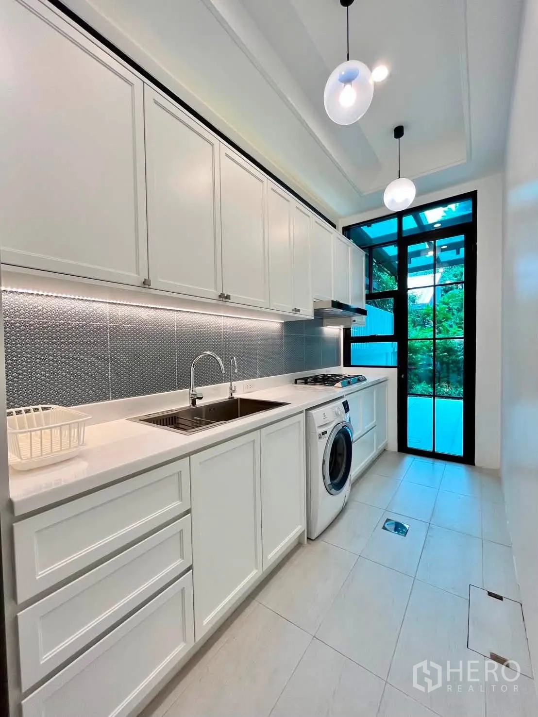 Townhouse for rent in Lat Phrao, Bangkok - Galley pantry kitchen with cabinetry, sink, cooktop and washing machine.