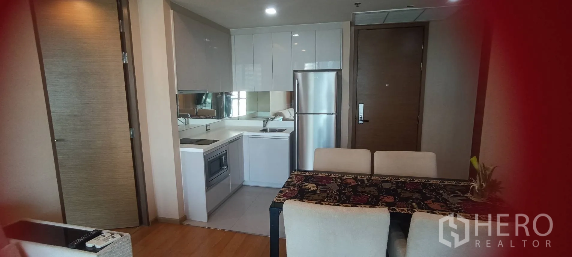 Condominium for rent or sale in Bang Rak, Bangkok - Open-plan kitchenette beside a dining table and the entrance door.