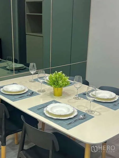 Condominium for sale in Watthana, Bangkok - Dining table set for four with tableware and mirror cabinetry backdrop.