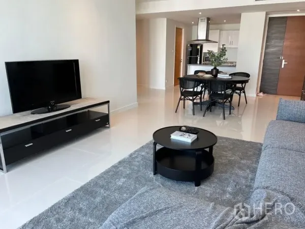 Condominium for rent in Watthana, Bangkok - Living area with TV console, round coffee table and glossy tiled floors in an open-plan layout.