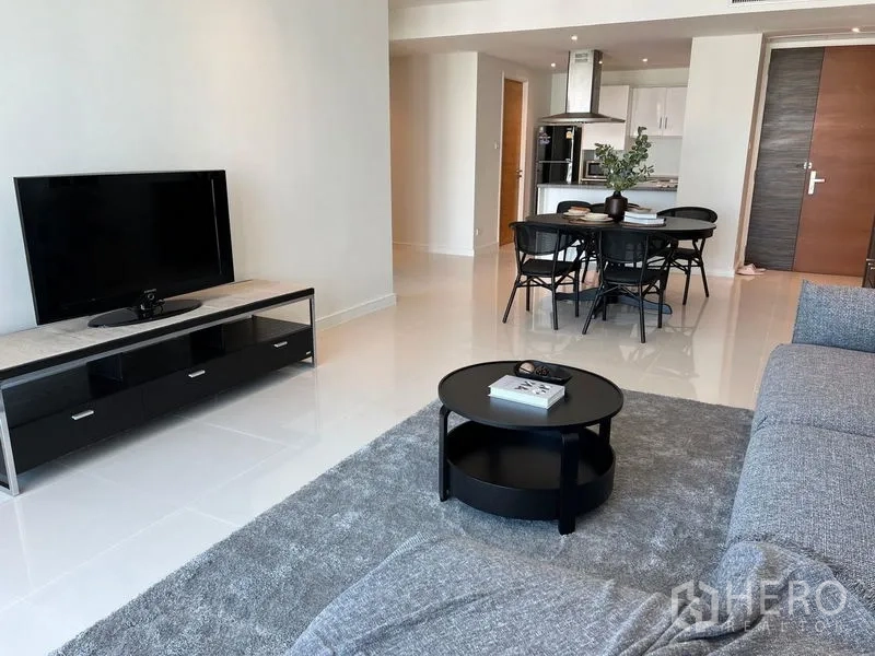 Condominium for rent in Watthana, Bangkok - Living area with TV console, round coffee table and glossy tiled floors in an open-plan layout.