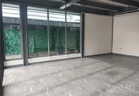 零售空间 出租在Khlong Toei, Bangkok - 整面玻璃墙面临绿植屏风，自然采光充足。