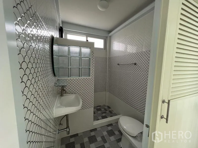 บ้าน ให้เช่าในKhlong Toei, Bangkok - ห้องน้ำกะทัดรัด กระเบื้องลายกราฟิก ฉากกั้นบล็อกแก้ว อ่างล้างมือและโถสุขภัณฑ์ ใต้หน้าต่างสูง