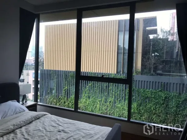 คอนโด ให้เช่าในKhlong Toei, Bangkok - ห้องนอนพร้อมหน้าต่างบานใหญ่ มองเห็นสวนและอาคารสมัยใหม่