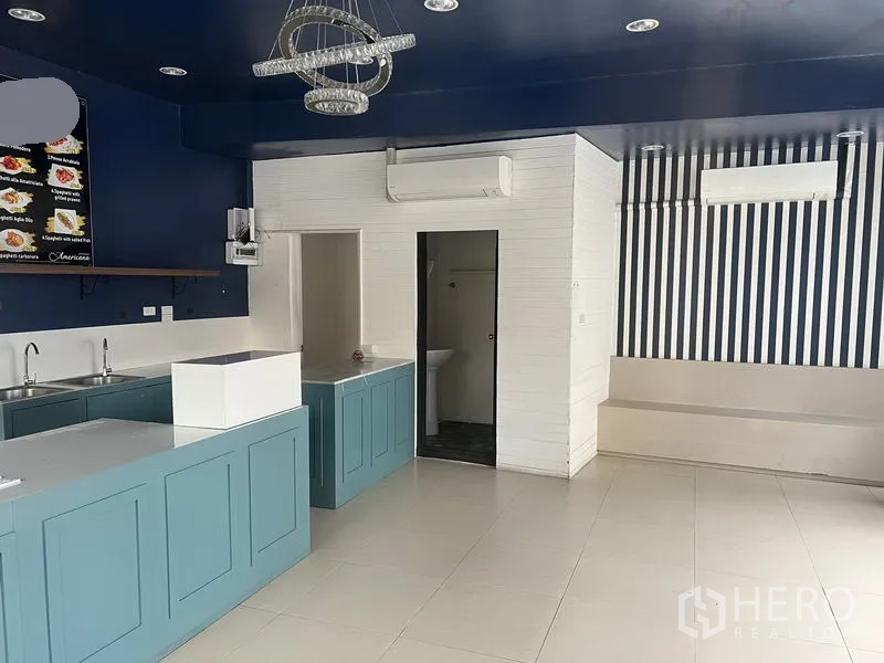 零售空间 出租在Watthana, Bangkok - 开放式零售区域，展示吧台、空调与通往卫生间的门。