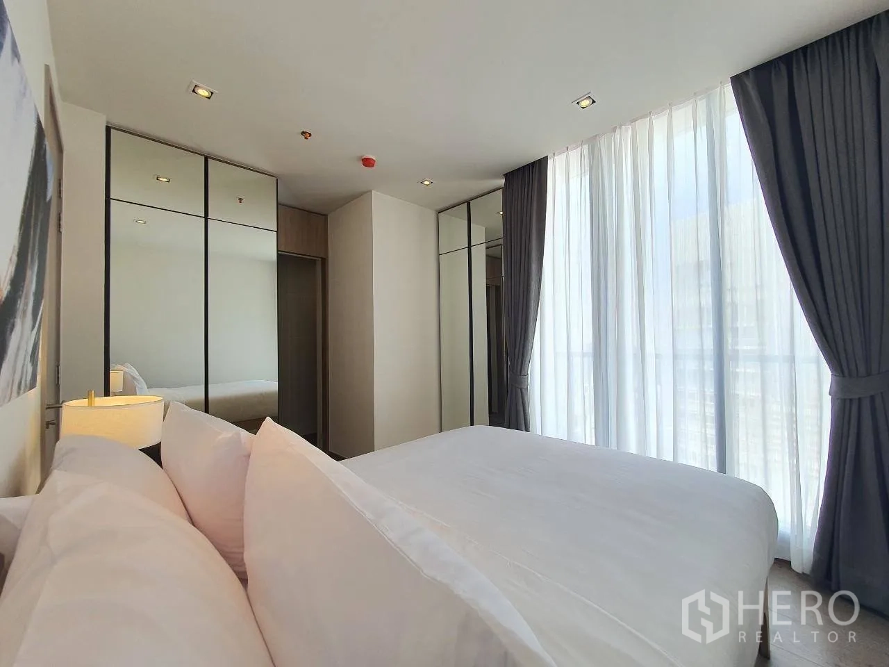 คอนโด for rent in Khlong Toei, Bangkok - ห้องนอนสว่างพร้อมหน้าต่างสูง ผ้าม่านทึบ และตู้เสื้อผ้าบานกระจก