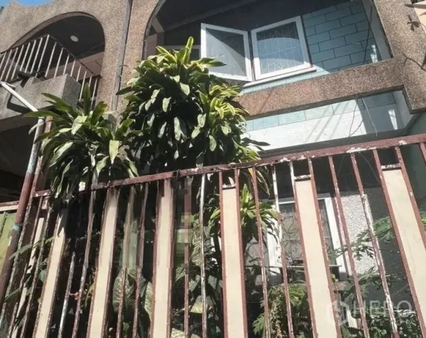 ทาวน์เฮาส์ ขาย - ด้านหน้าทาวน์เฮาส์ 2 ชั้นย่านเอกมัย มีระเบียงโค้ง หน้าต่างเปิด และต้นไม้ใหญ่หลังรั้วเหล็ก