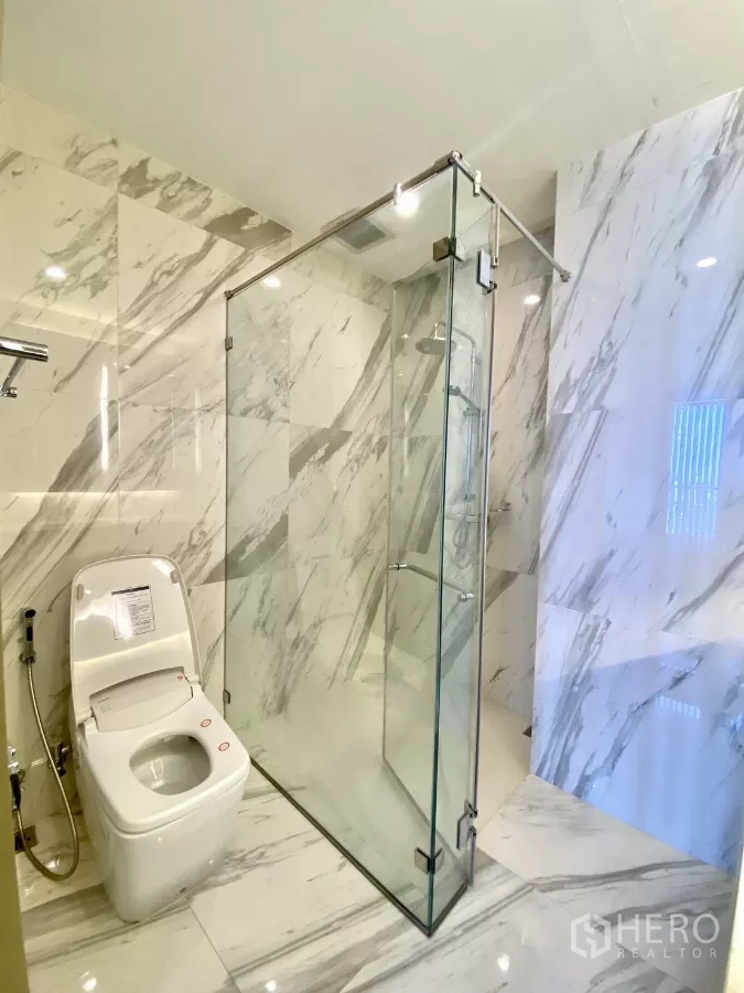 คอนโด ขายในPathum Wan, Bangkok - ห้องน้ำพร้อมตู้กระจกกั้นอาบน้ำแบบเรนชาวเวอร์ และโถสุขภัณฑ์บนพื้นผนังหินอ่อน
