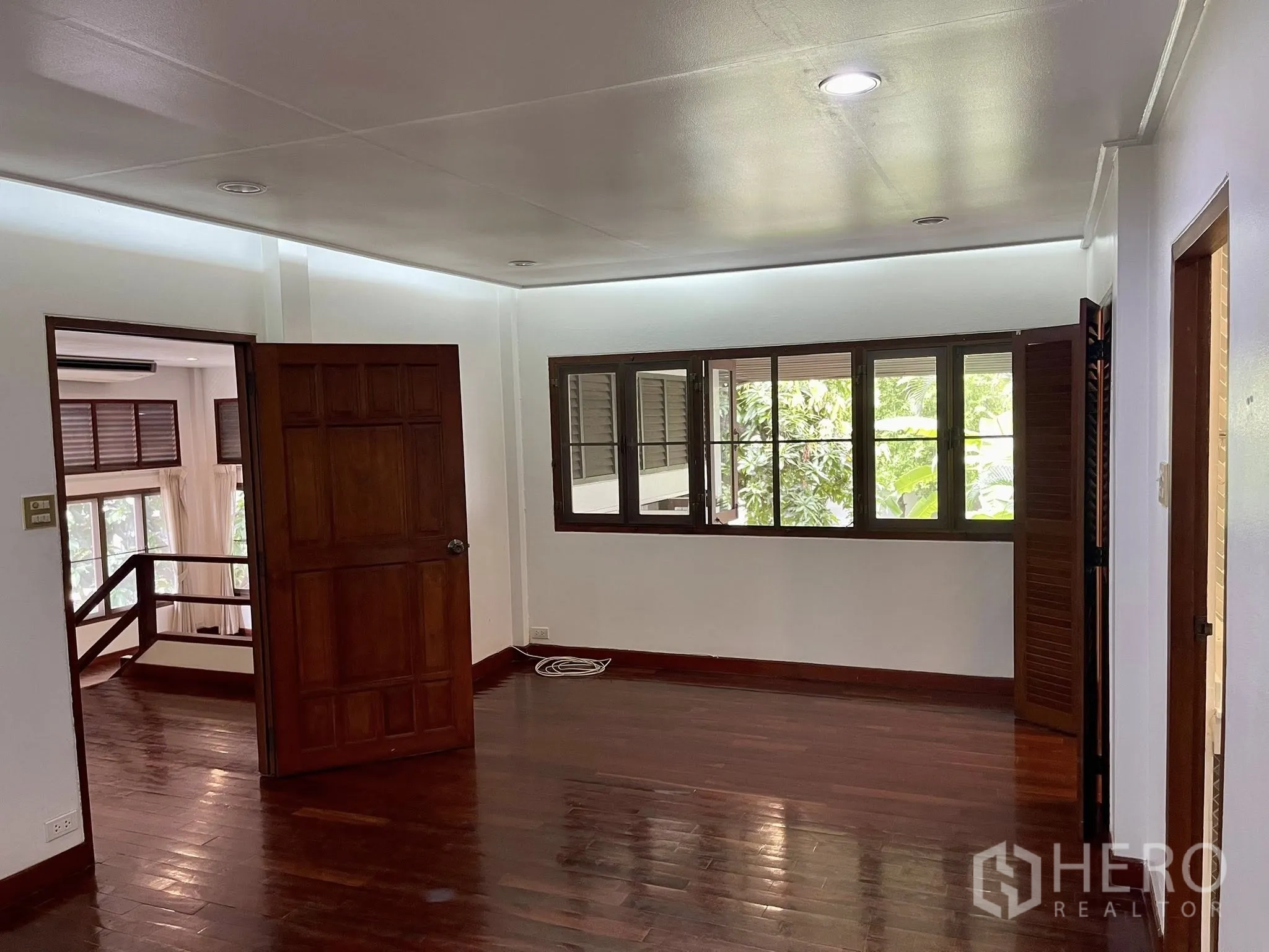 บ้านเดี่ยว for rent in Pathum Wan, Bangkok - ห้องสว่างพื้นไม้จริง ประตูกับหน้าต่างไม้เห็นวิวต้นไม้