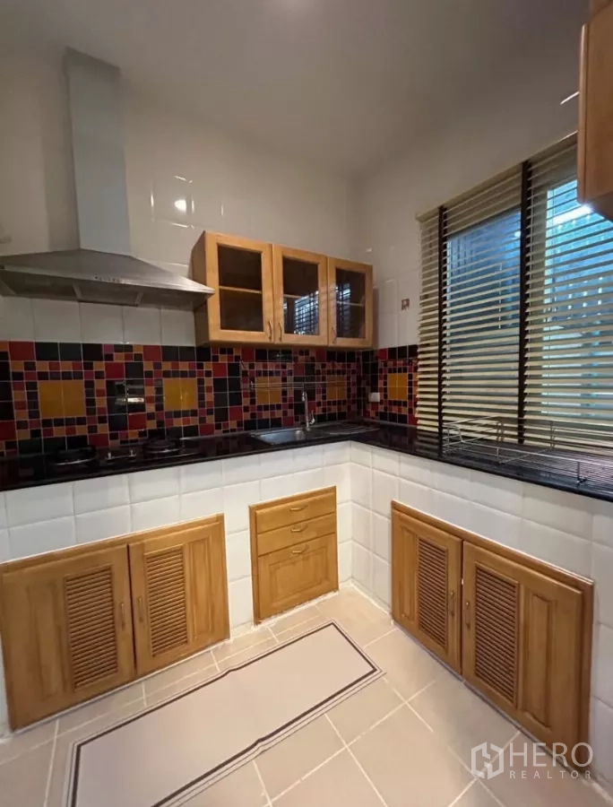 Townhouse for rent in Wang Thonglang, Bangkok - U-shaped kitchen with wooden cabinets, black granite counters and colorful backsplash