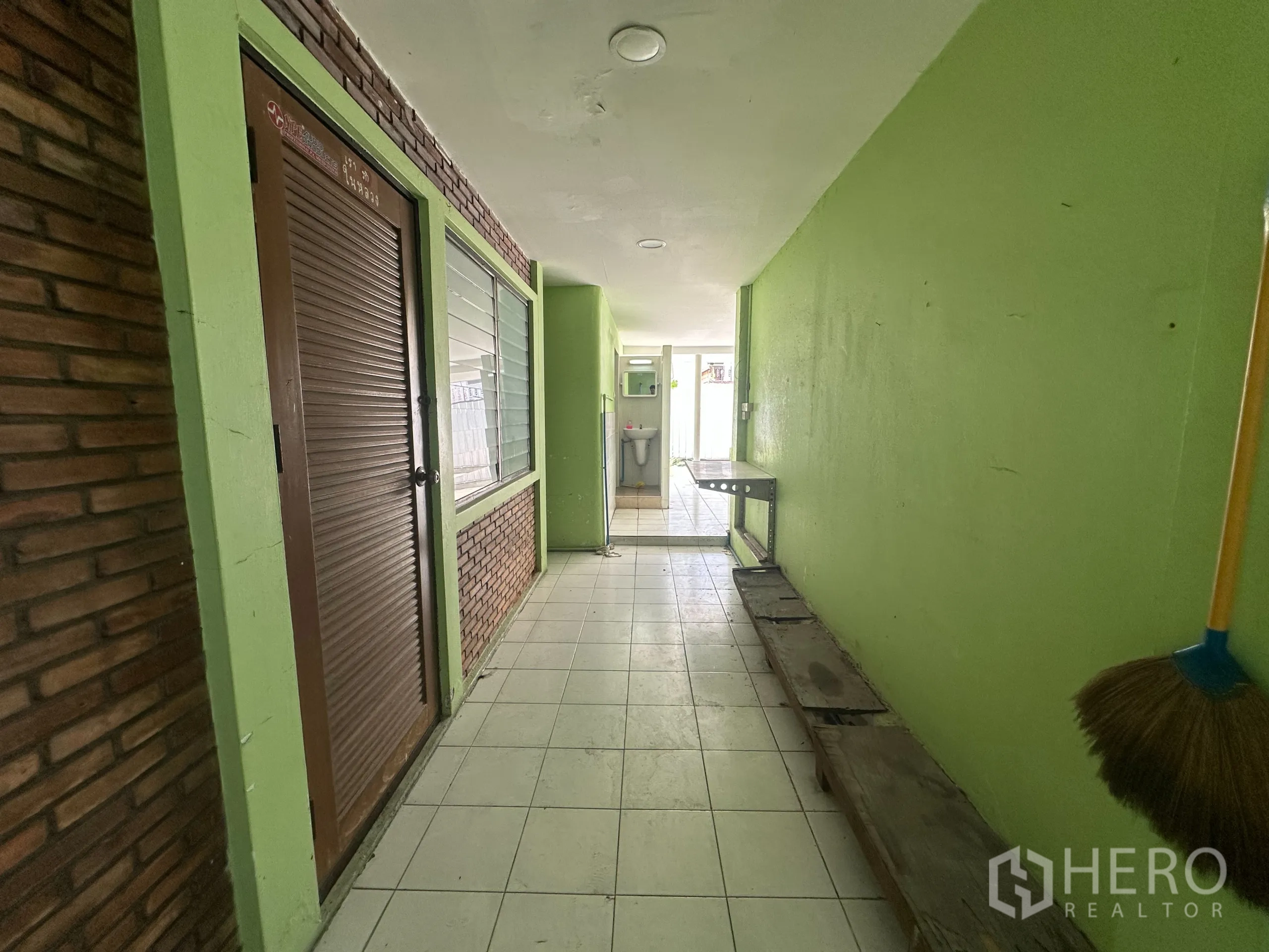 零售空间 出租在Watthana, Bangkok - 覆盖式侧走廊，绿色墙面与砖饰，通向服务区。