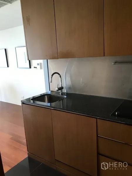 公寓 出租在Pathum Wan, Bangkok - 小型厨房，木质橱柜、黑色石材台面与不锈钢挡板
