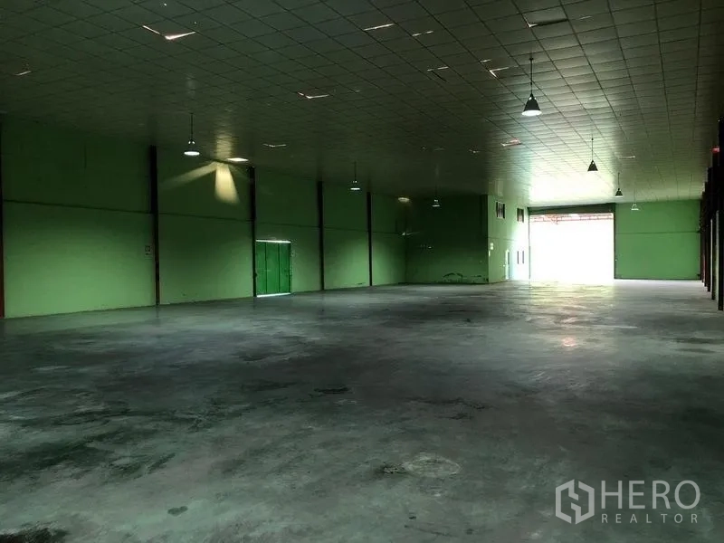 Factory for rent in Sam Khok, Pathum Thani - Vast indoor warehouse with high ceiling, pendant lights, and rear loading door.