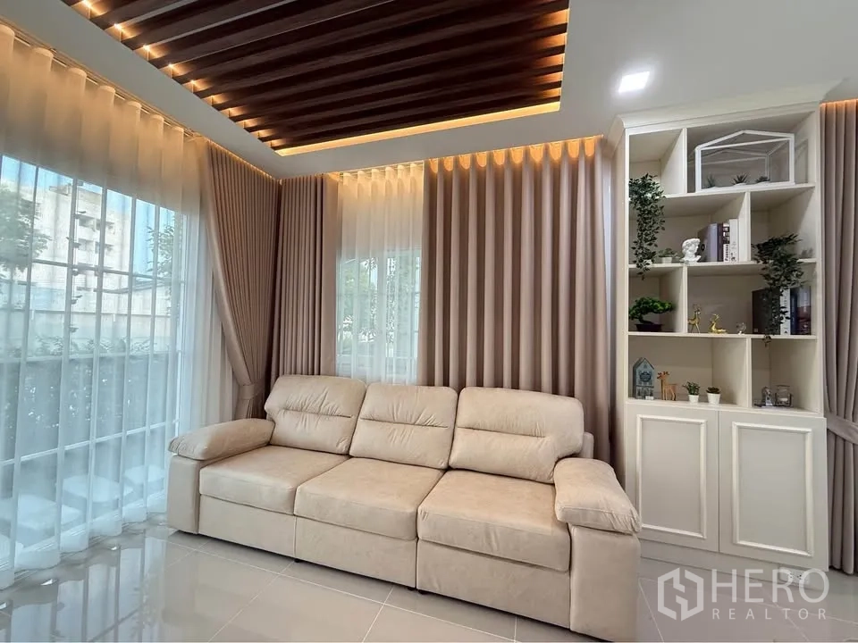 บ้านแฝด for rent in Mueang Samut Prakan, Samut Prakan - ห้องนั่งเล่นมุมโซฟาสีเบจ กระจกบานใหญ่ และชั้นบิวท์อิน