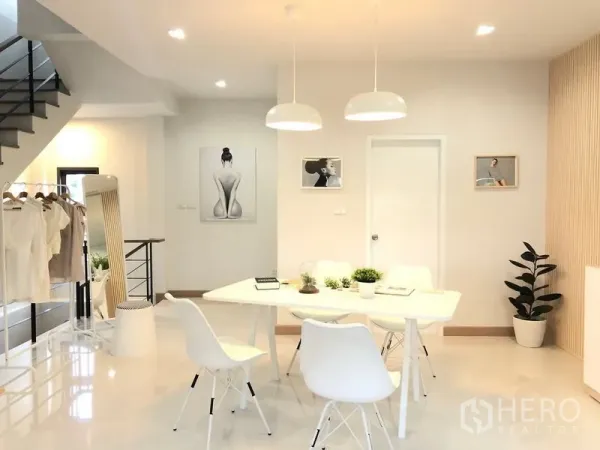 Shophouse for rent in Lat Phrao, Bangkok - Another angle of the white meeting space near the stairway with indoor plants and framed wall art.