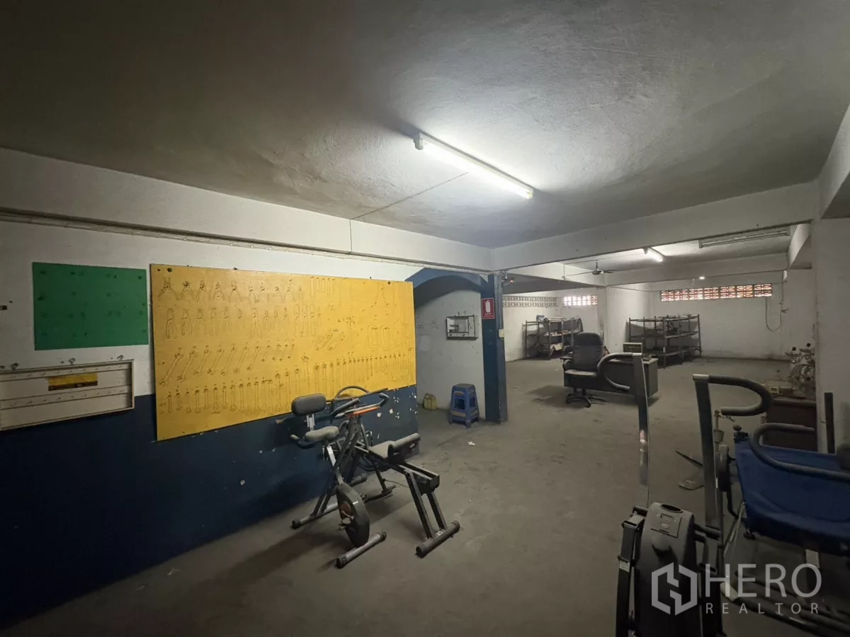 Warehouse for rent in Khlong Toei, Bangkok - Multipurpose room in the warehouse with exercise equipment and metal racks.
