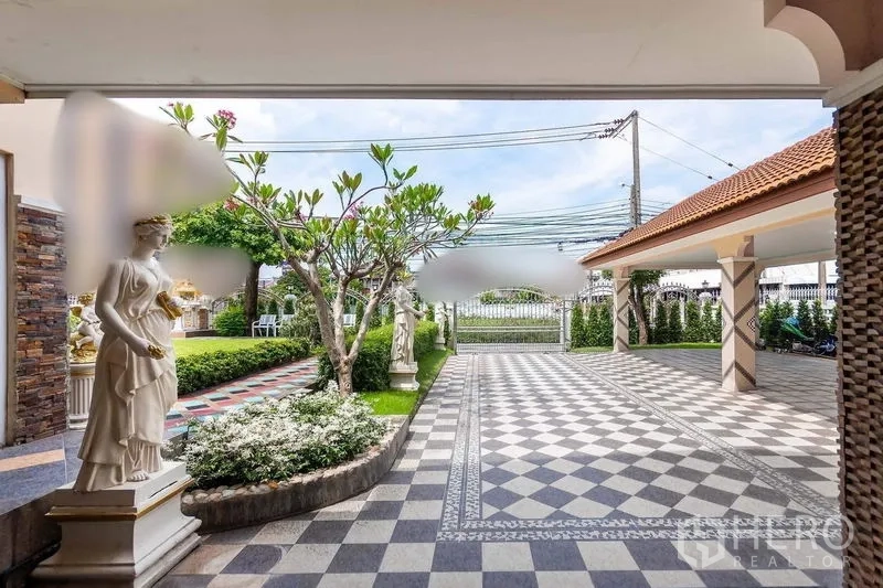 独立式住宅 出租或出售在Bang Khen, Bangkok - 宽阔的半露天车棚与棋盘格车道，搭配园林雕像与绿篱，面向前门。
