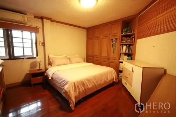 Detached House for rent in Bang Phli, Samut Prakan - Cozy bedroom with wood flooring, built-in wardrobes and a window with blinds.