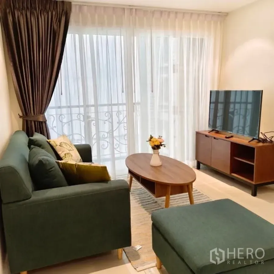 Condominium for rent in Watthana, Bangkok - Living room view showing balcony railings, oval coffee table and media console in a Watthana condominium.