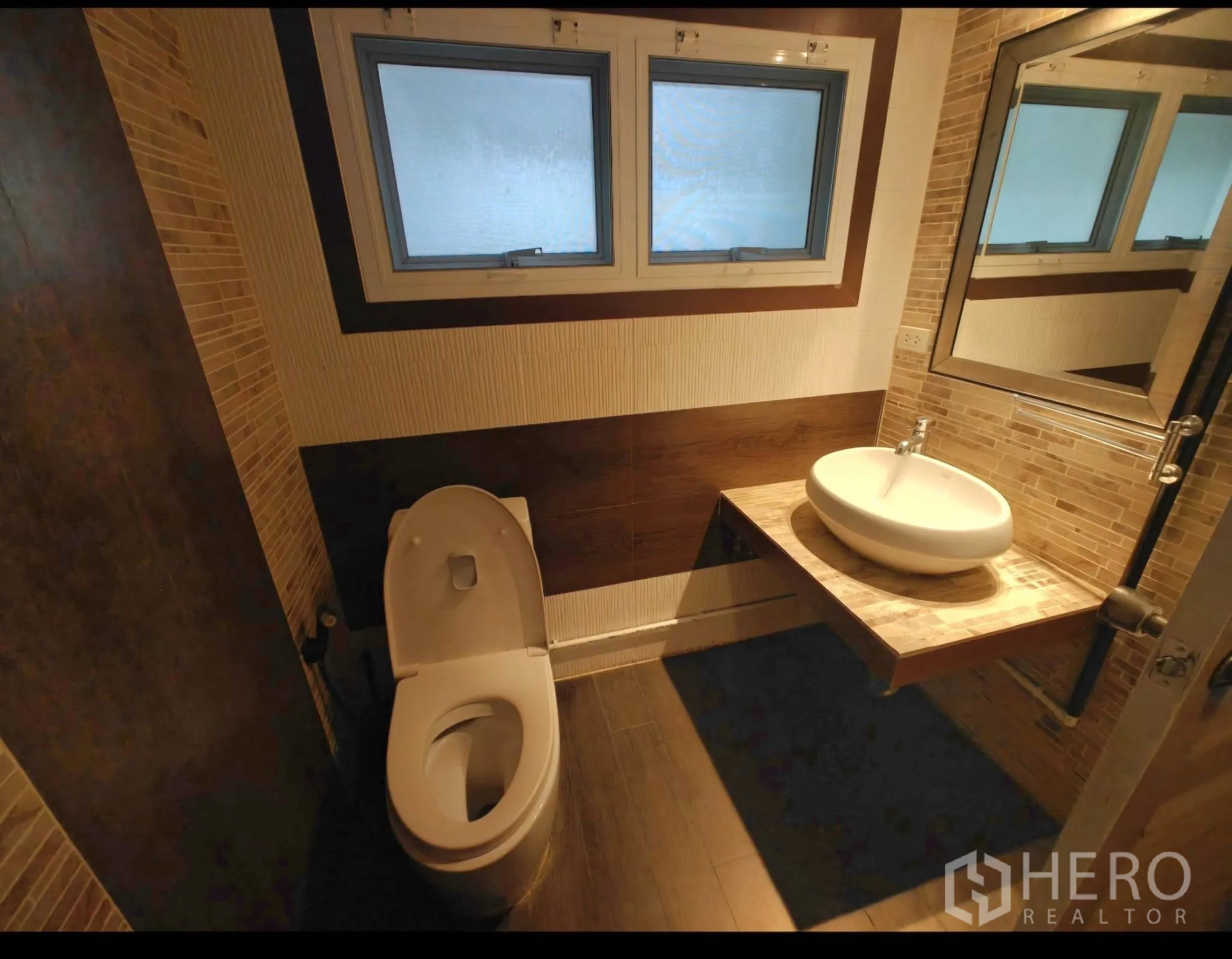 Condominium for rent in Sathon, Bangkok - Bathroom with vessel sink on a floating counter, frosted windows, and warm-toned tiles.