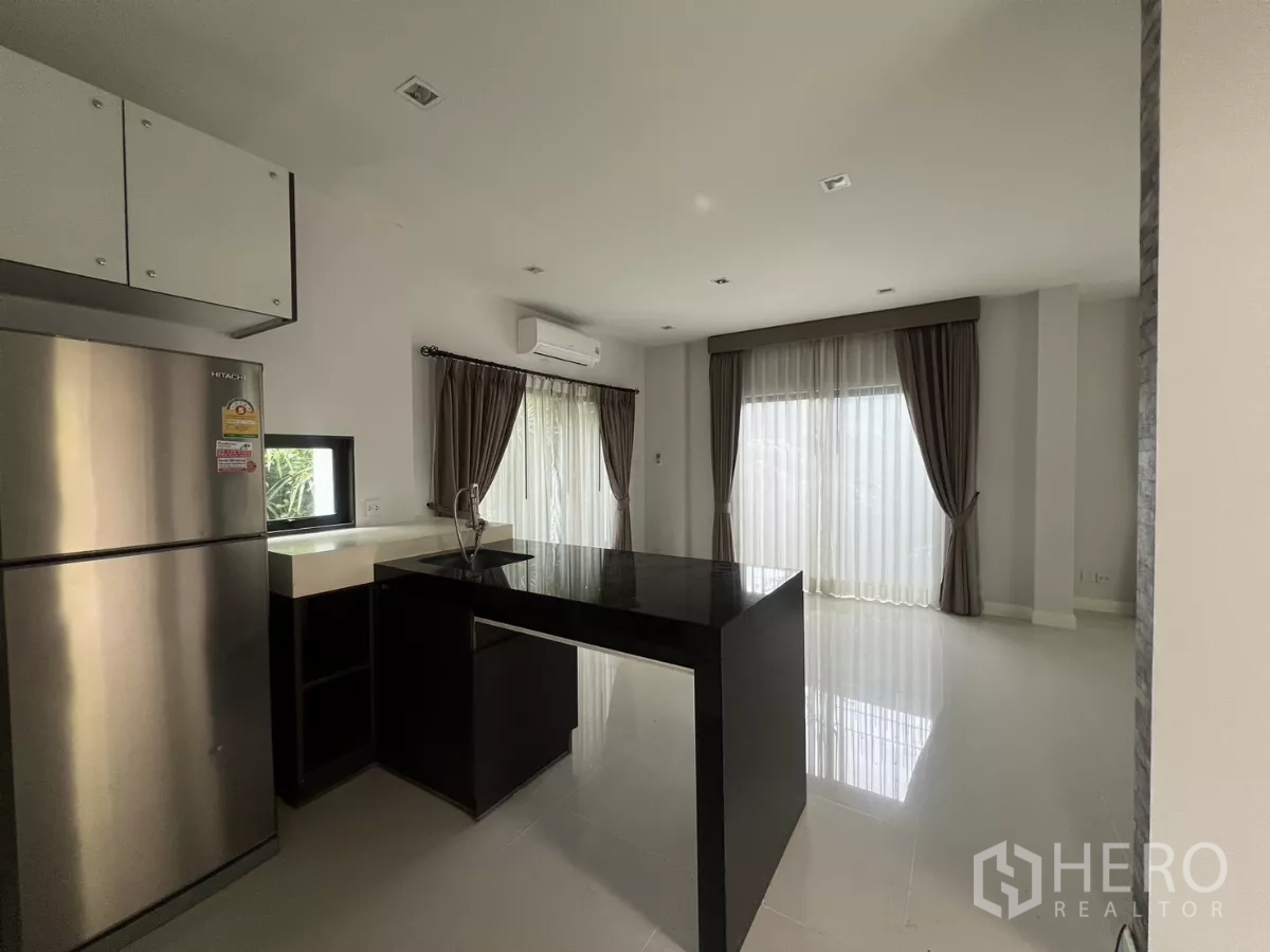 Detached House for sale in Bang Kapi, Bangkok - Kitchen zone with black countertop peninsula, stainless refrigerator, and wide windows with curtains.