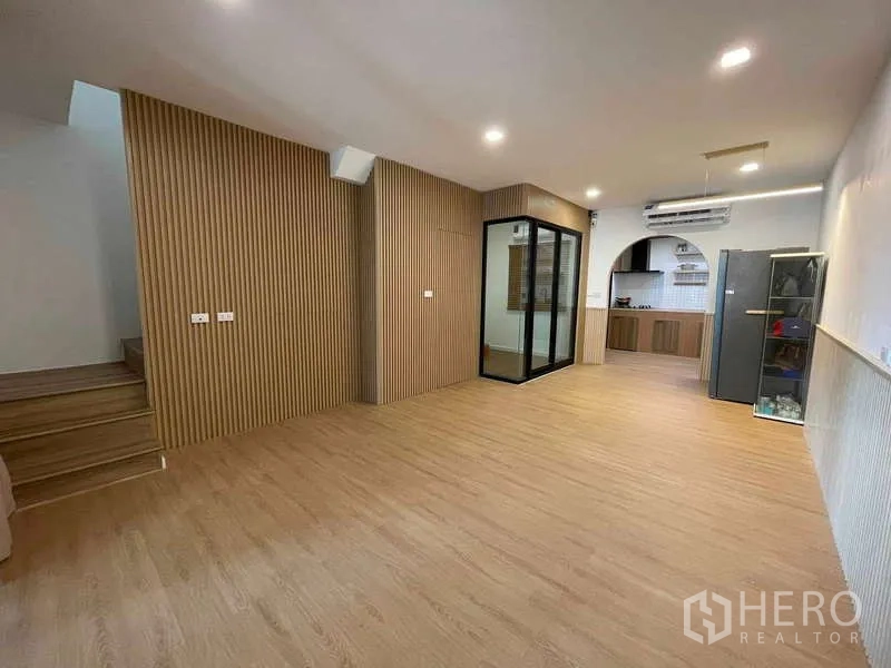 Townhouse for rent or sale in Bang Kapi, Bangkok - Open living space with wood slat feature walls and a stair to the upper floor.