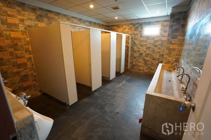 โรงงาน ขายในKhlong Luang, Pathum Thani - ห้องน้ำรวมมีหลายห้องแยก ผนังลายอิฐ และอ่างล้างมือคอนกรีตยาว