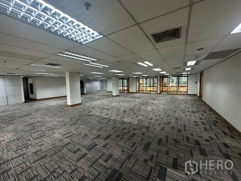 Office Space for rent in Khlong Toei, Bangkok - Spacious grey-carpeted office area with suspended ceiling and city outlook.