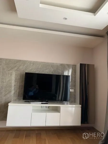 คอนโด ให้เช่าในWatthana, Bangkok - มุมนั่งเล่นมีทีวีจอแบนบนตู้สีขาวและผนังตกแต่งลายหิน
