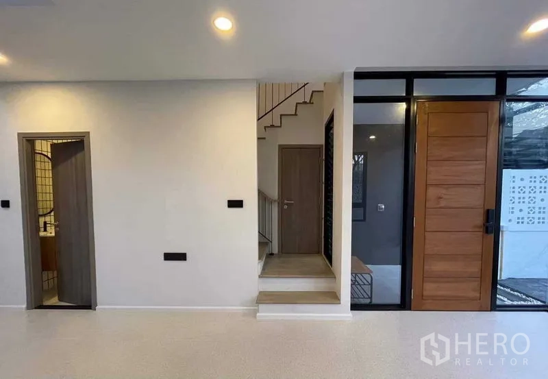 สำนักงานที่บ้าน ขายในLat Phrao, Bangkok - โถงทางเข้าพร้อมประตูไม้ บันได และห้องน้ำแขก