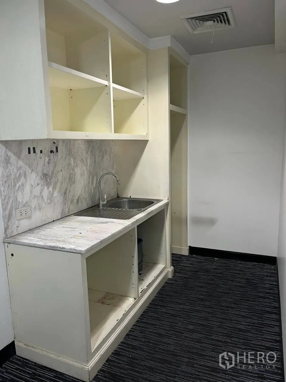 Office Space for rent in Khlong Toei, Bangkok - Compact office pantry with sink, marble-look backsplash, and open cabinets.