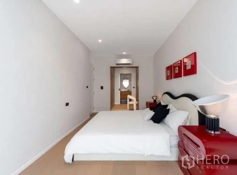 Townhouse for sale in Sathon, Bangkok - Spacious bedroom looking toward doorway with built-in air conditioner and minimalist decor.