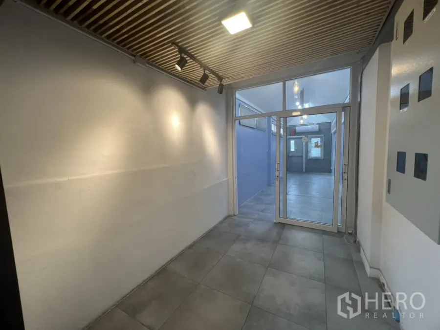 พื้นที่ขายปลีก ให้เช่า - โถงทางเข้าเพดานไม้ซี่ ไฟสปอต และประตูกระจกสู่ยูนิตค้าปลีกขนาดกะทัดรัด