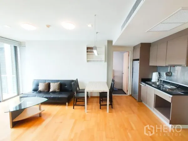 คอนโด ให้เช่าในKhlong Toei, Bangkok - ห้องนั่งเล่นแบบเปิดโล่งเชื่อมครัว โต๊ะทานอาหาร โซฟาหนัง และโต๊ะกลางกระจก บนพื้นไม้