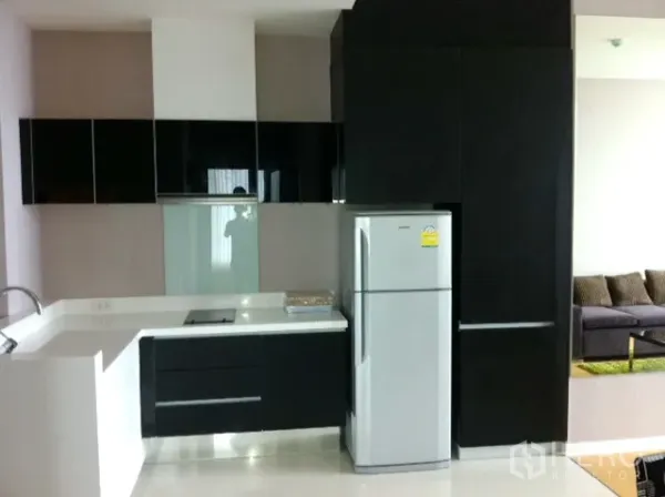 คอนโด ให้เช่าในWatthana, Bangkok - ครัวรูปตัวแอลตู้เงาสีดำ ท็อปสีขาว เตาไฟฟ้า และตู้เย็นขนาดใหญ่