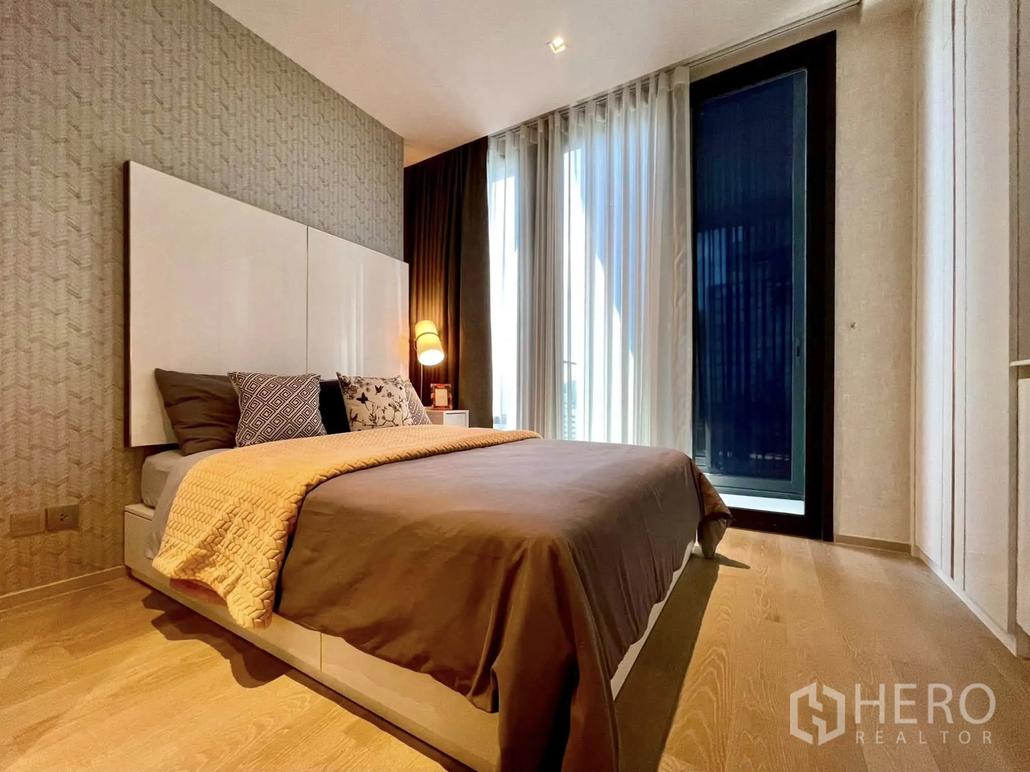 Condominium for rent in Bang Rak, Bangkok - Cozy bedroom with double bed, bedside lamp and sheer curtains.