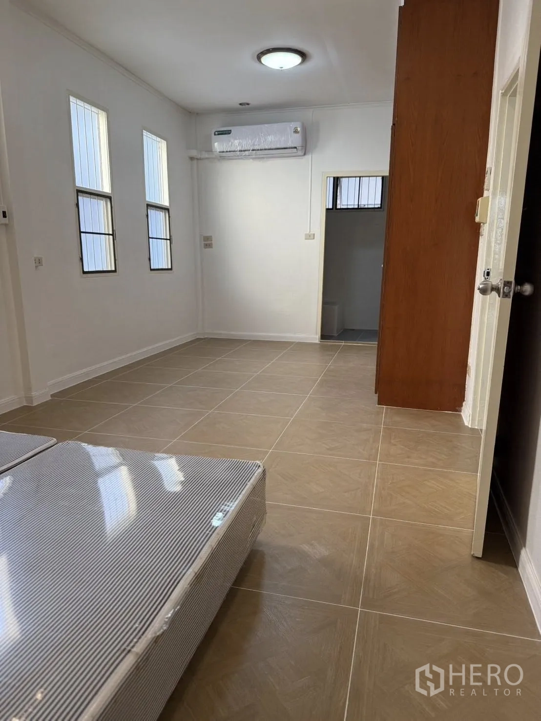 บ้านเดี่ยว for rent in Khlong Toei, Bangkok - ห้องปูพื้นกระเบื้องสว่าง มีหน้าต่างสูง แอร์ และประตูทางเข้าห้องน้ำ