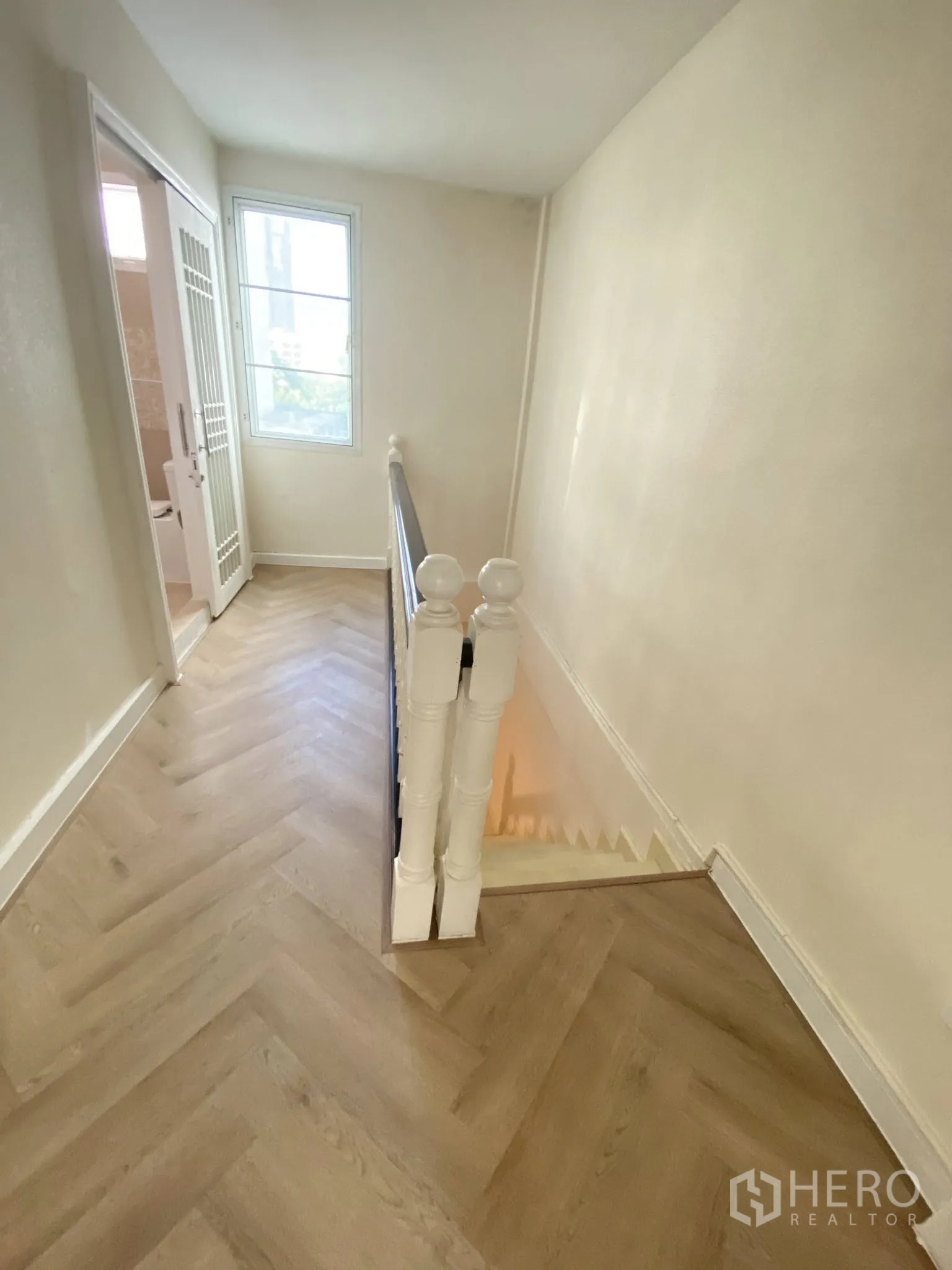 Home Office for rent in Pathum Wan, Bangkok - Bright stair landing with a window and light wood flooring leading to upper rooms.