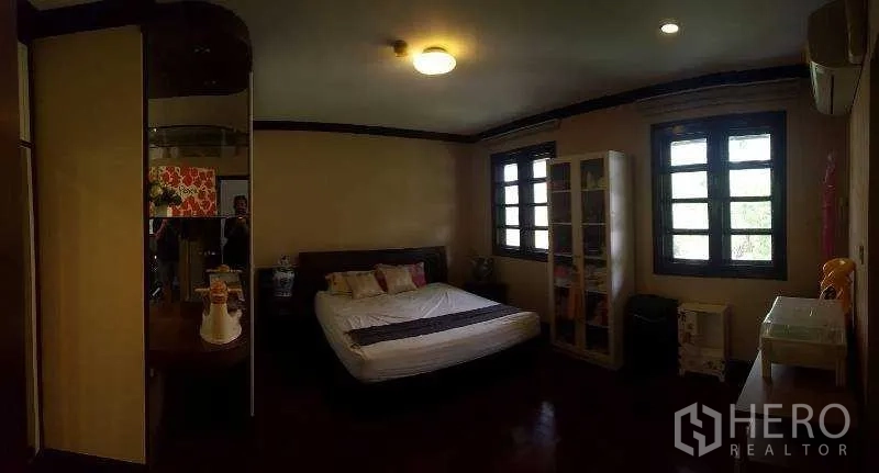 Detached House for rent in Bang Phli, Samut Prakan - Bedroom with dark wood floors, shelving unit and twin windows.