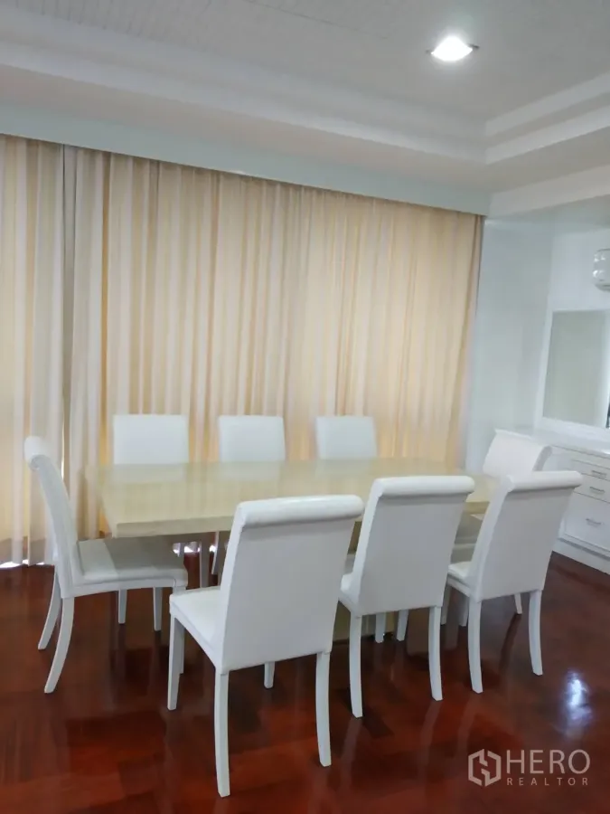 Condominium for rent in Pathum Wan, Bangkok - Bright dining room with eight white chairs, large table and full-height curtains on polished wood floors.