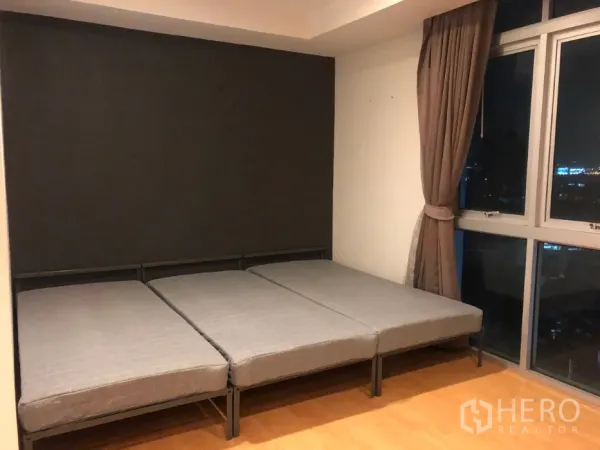 公寓 出售在Khlong Toei, Bangkok - 卧室配低矮床架，转角落地窗与窗帘，可见城市天际线