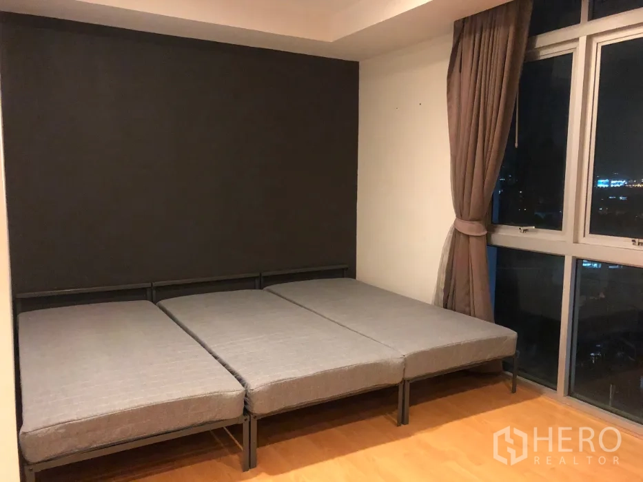 公寓 出售在Khlong Toei, Bangkok - 卧室配低矮床架，转角落地窗与窗帘，可见城市天际线