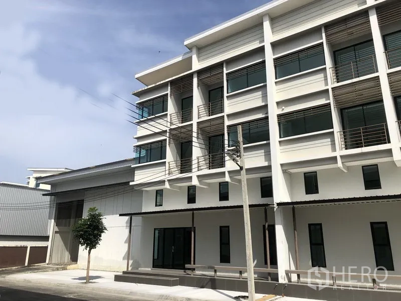 Factory for rent or sale in Bang Bua Thong, Nonthaburi - Close view of the contemporary office facade beside the warehouse loading bay.